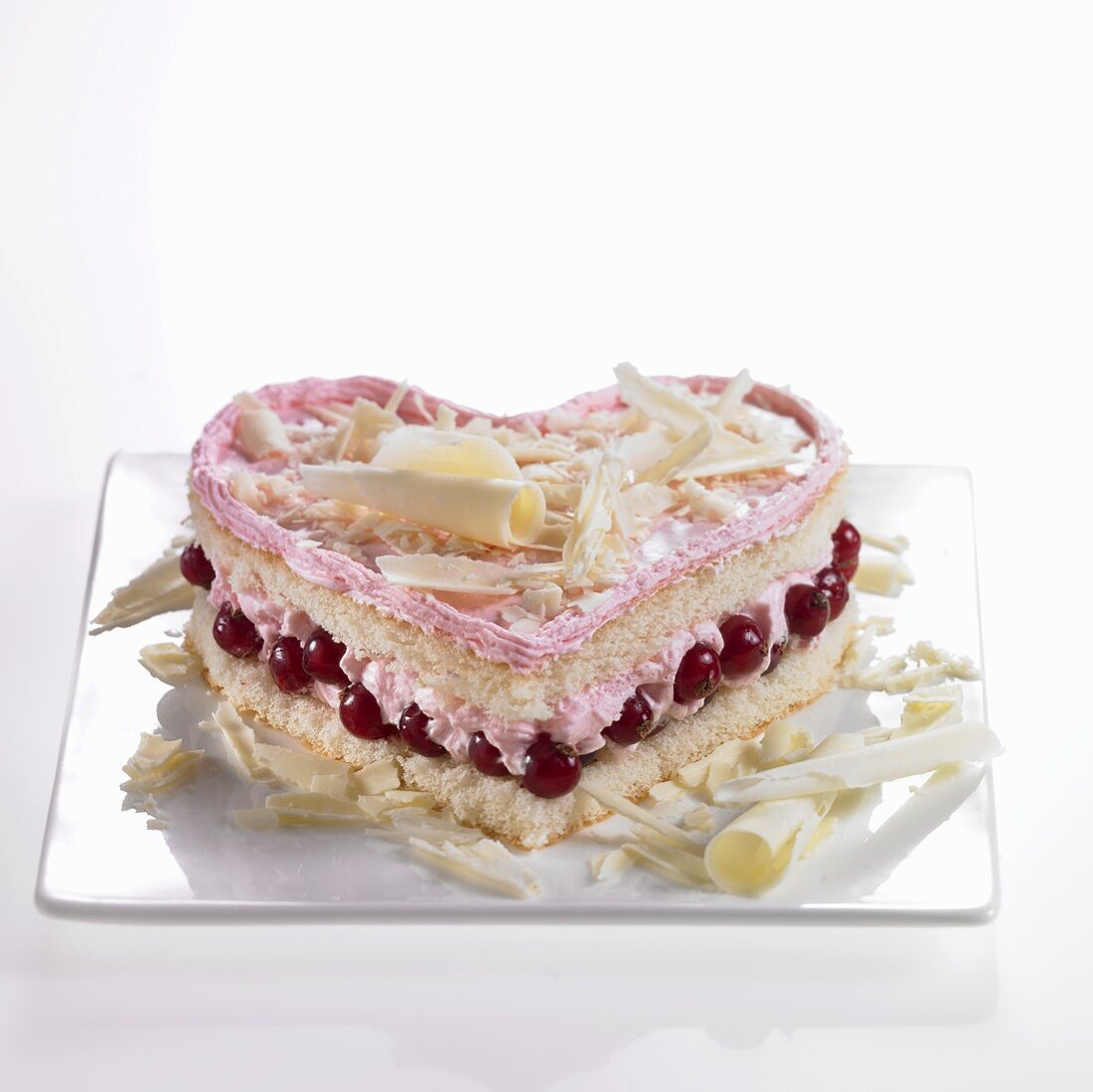Heart-shaped sponge cake with redcurrants, cream and white chocolate