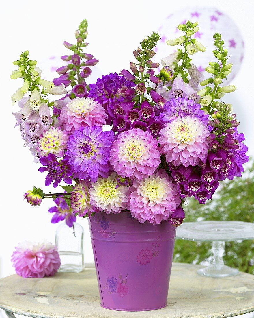 Arrangement of dahlias & other summer flowers in pink on garden table