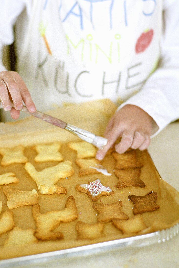 Child brushing biscuits with glacé icing