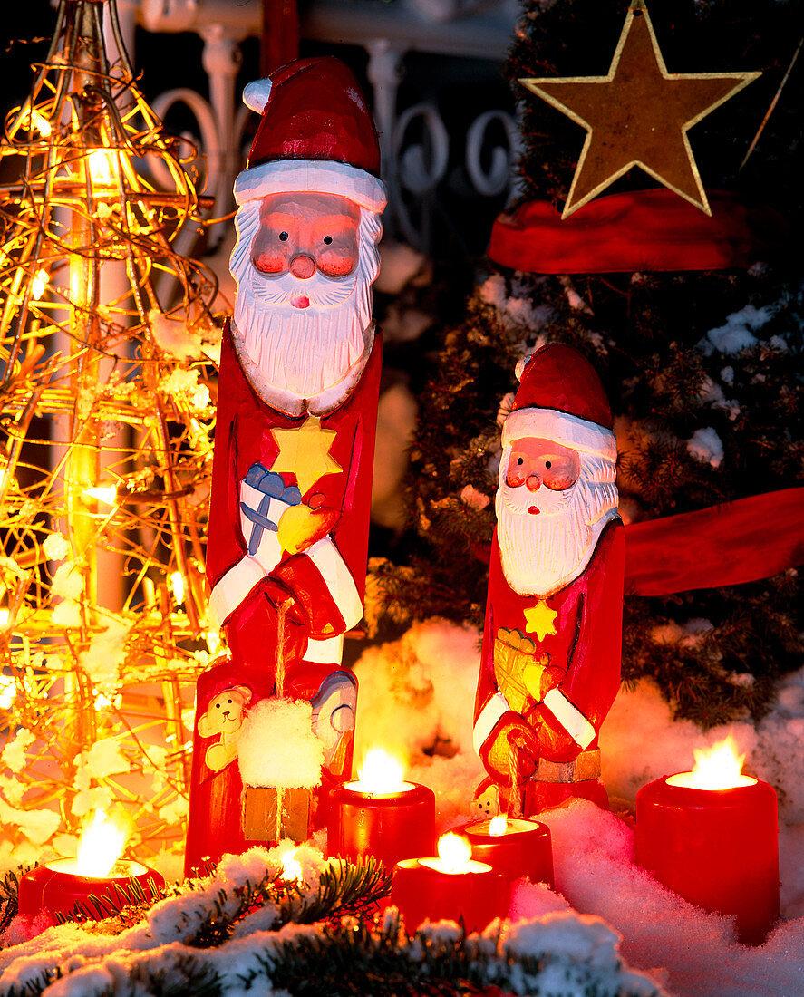 Father Christmases in snow with fairy lights