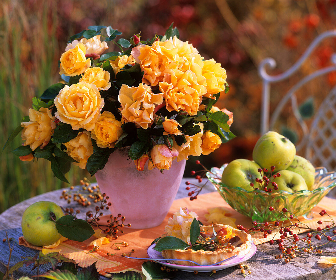 An arrangement of yellow roses, rose hips and apple quinces