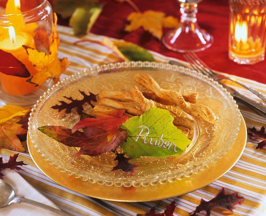 Salzgebäck auf Glasteller, mit Herbstlaub und Blatt mit Namen