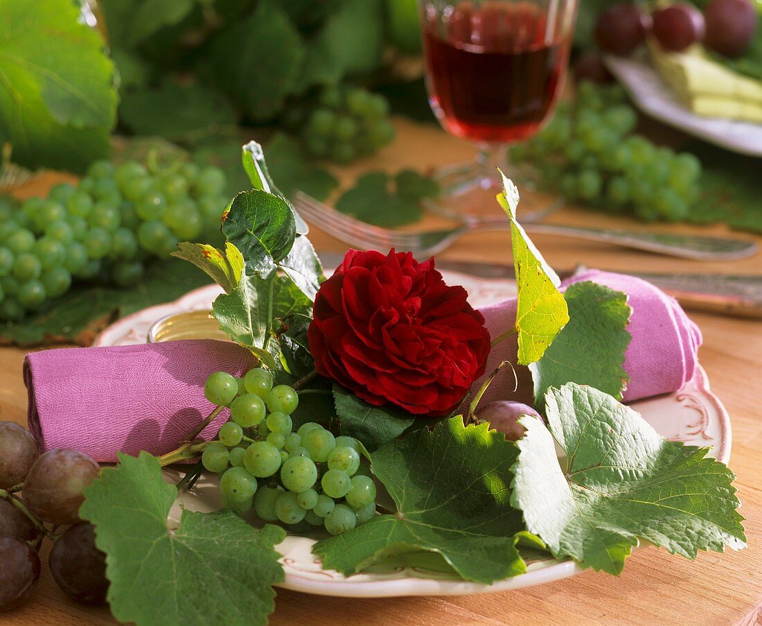 Dark red rose with grapes and vine leaves - table decoration
