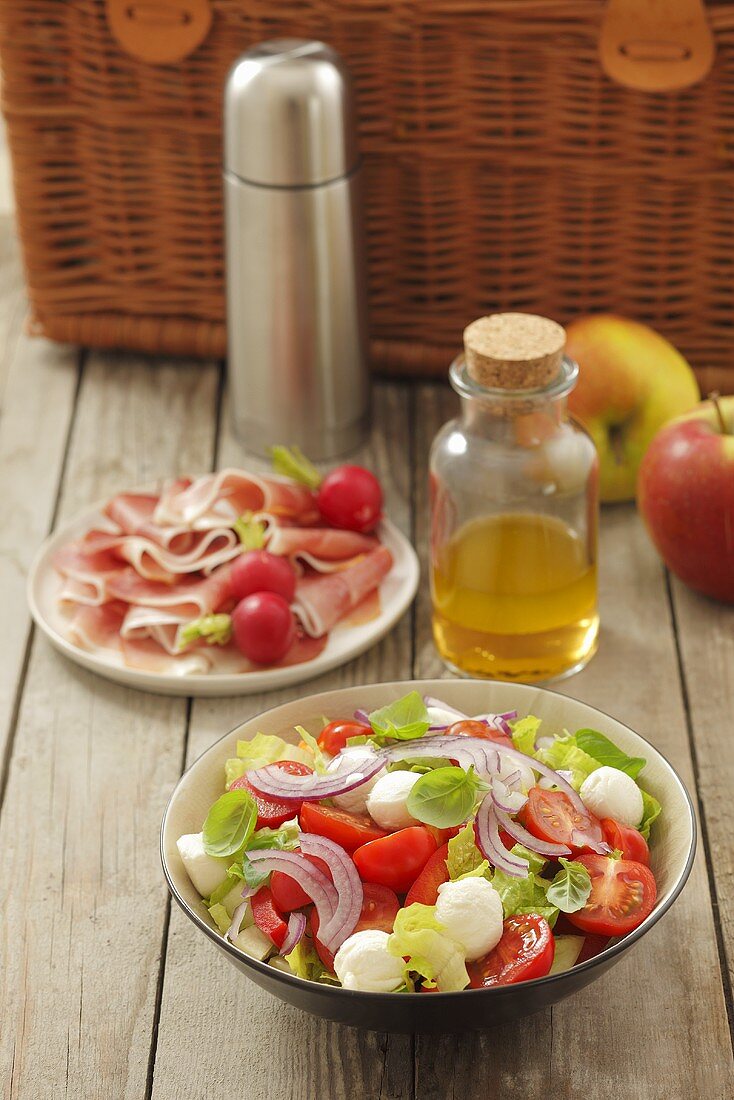 Tomato and mozzarella salad and ham with radishes for a picnic