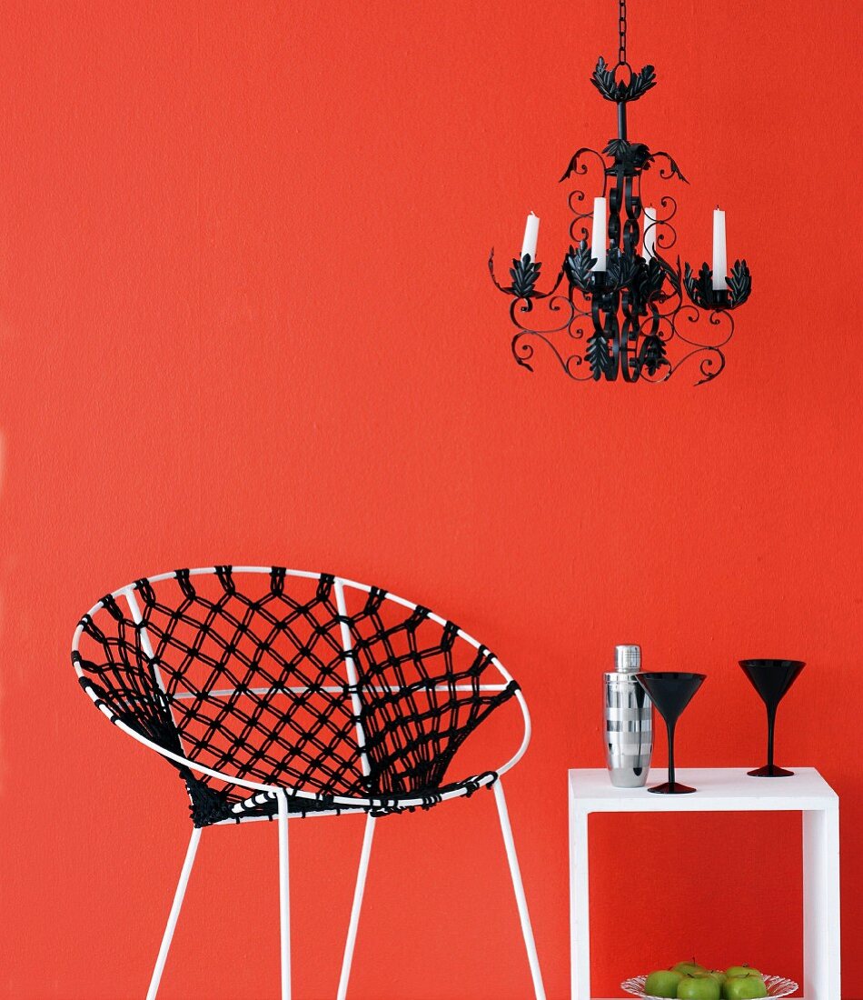 Stuhl mit Makramee und ein Beistelltisch vor roter Wand