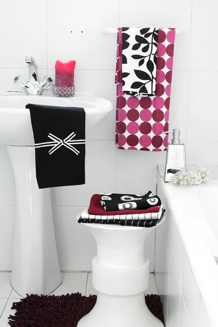 Various towels on stool and wash basin next to bathtub