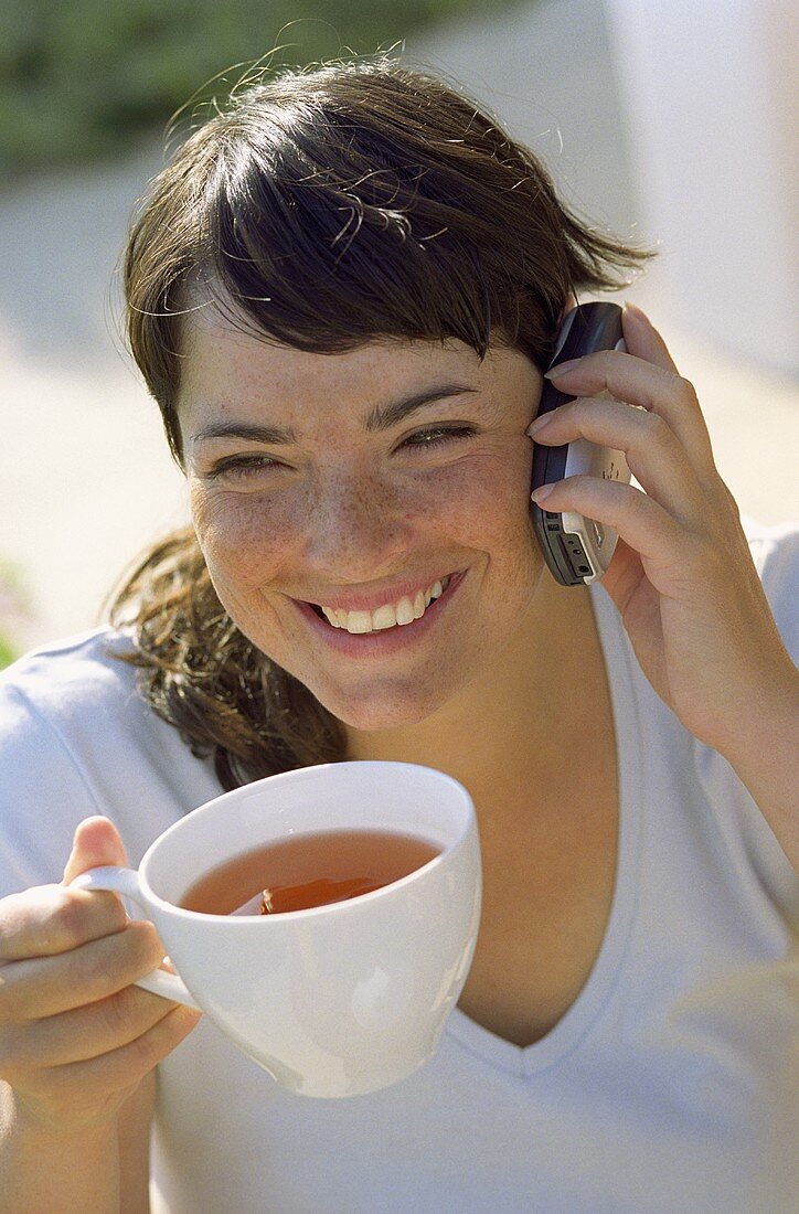 Junge Frau mit Teetasse und Handy