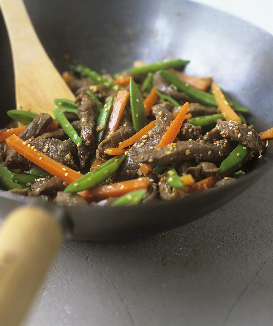 Strips of beef with vegetables and sesame seeds in a wok