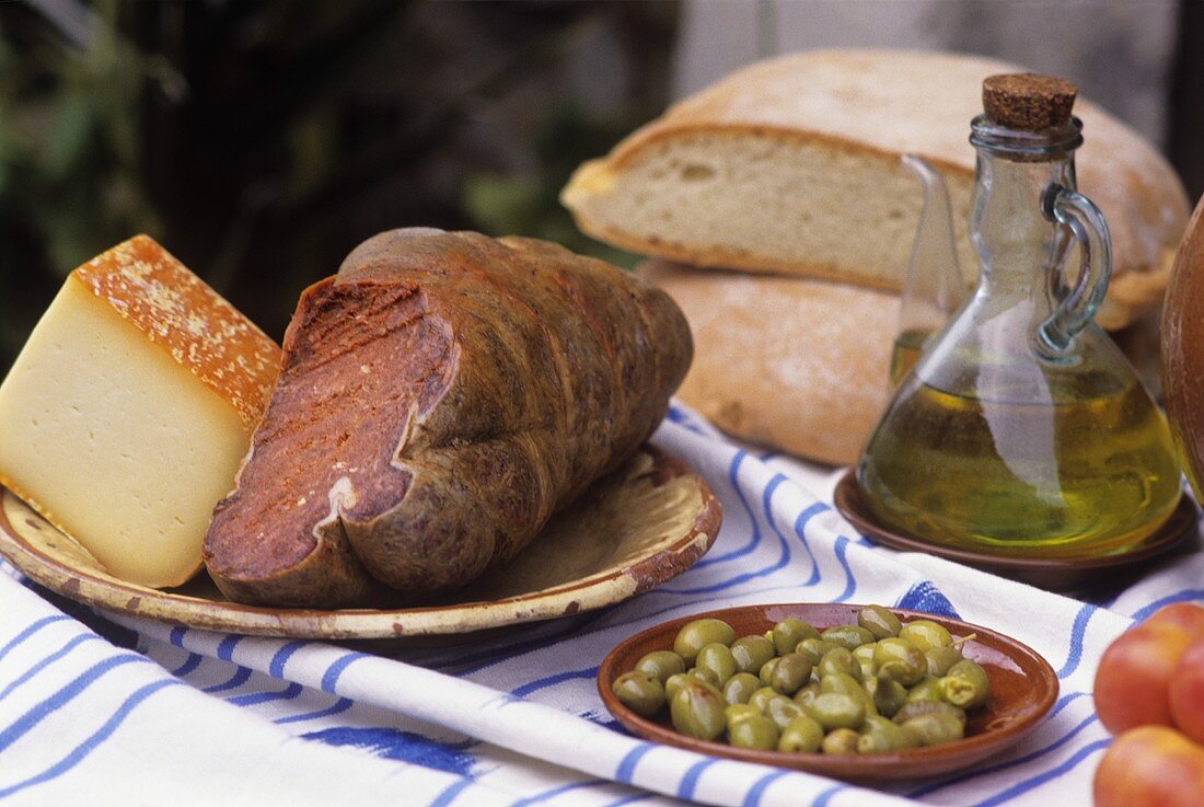 Stillleben mit Käse, Botifarrón, Oliven, Olivenöl (Mallorca)