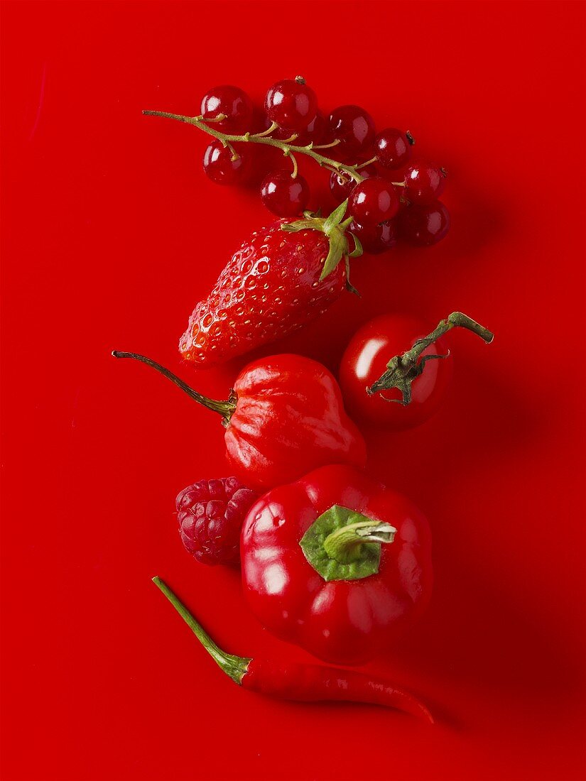 Rote Beeren und Gemüse vor rotem Hintergrund