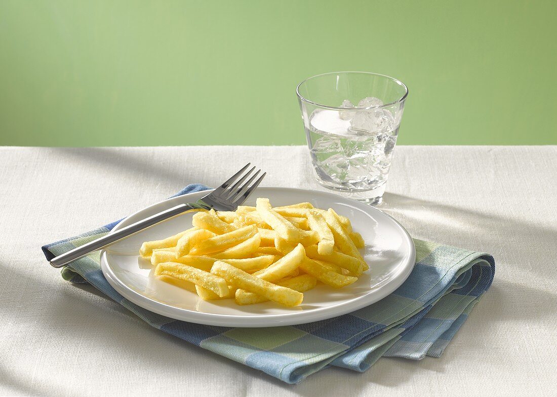 Pommes Frites und ein Glas Wasser mit Eiswürfeln