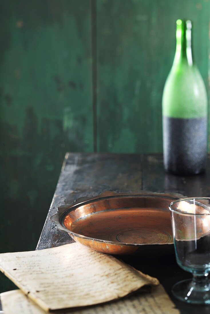 Copper dish, bottle of wine and old exercise books