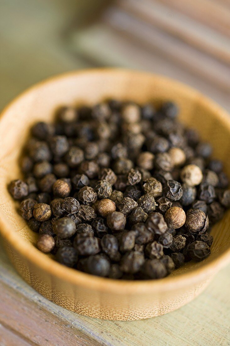 Black peppercorns in a small wooden dish