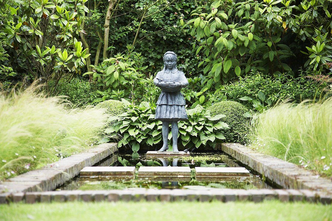 Stone figure by garden pond