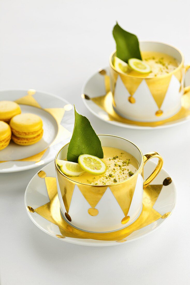 Lime panna cotta in two cups and saucers with macarons