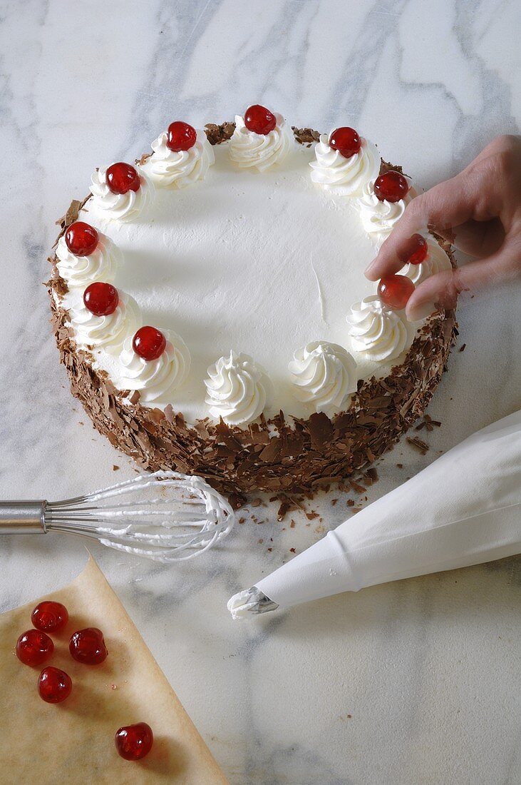 Decorating Black Forest gateau with cherries