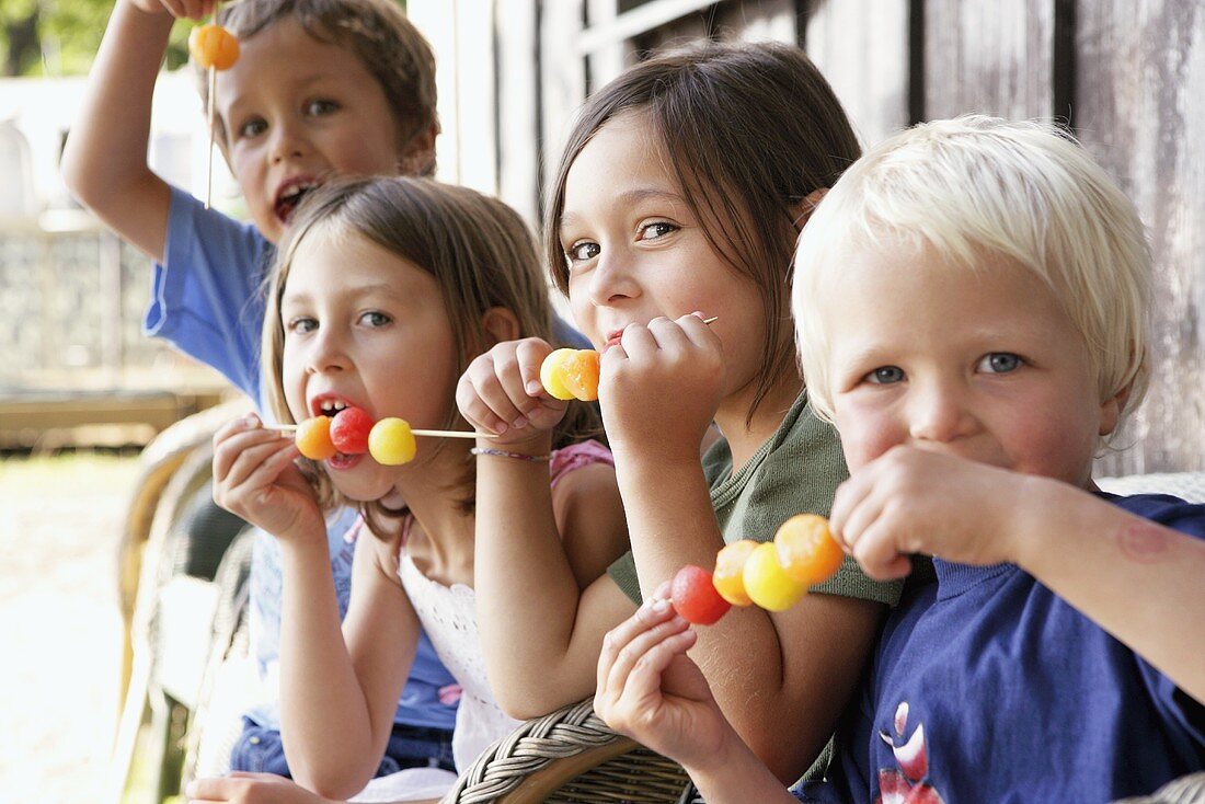 Four children eating melon skewers