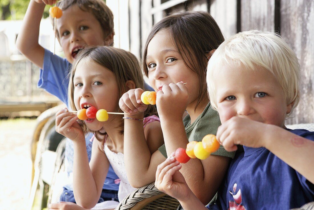 Vier Kinder essen Melonen-Spiesse