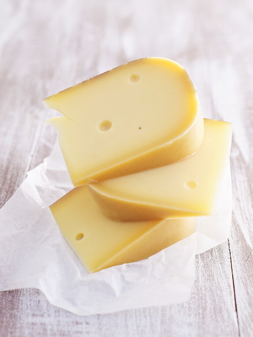 Pieces of Gouda cheese, stacked, on paper