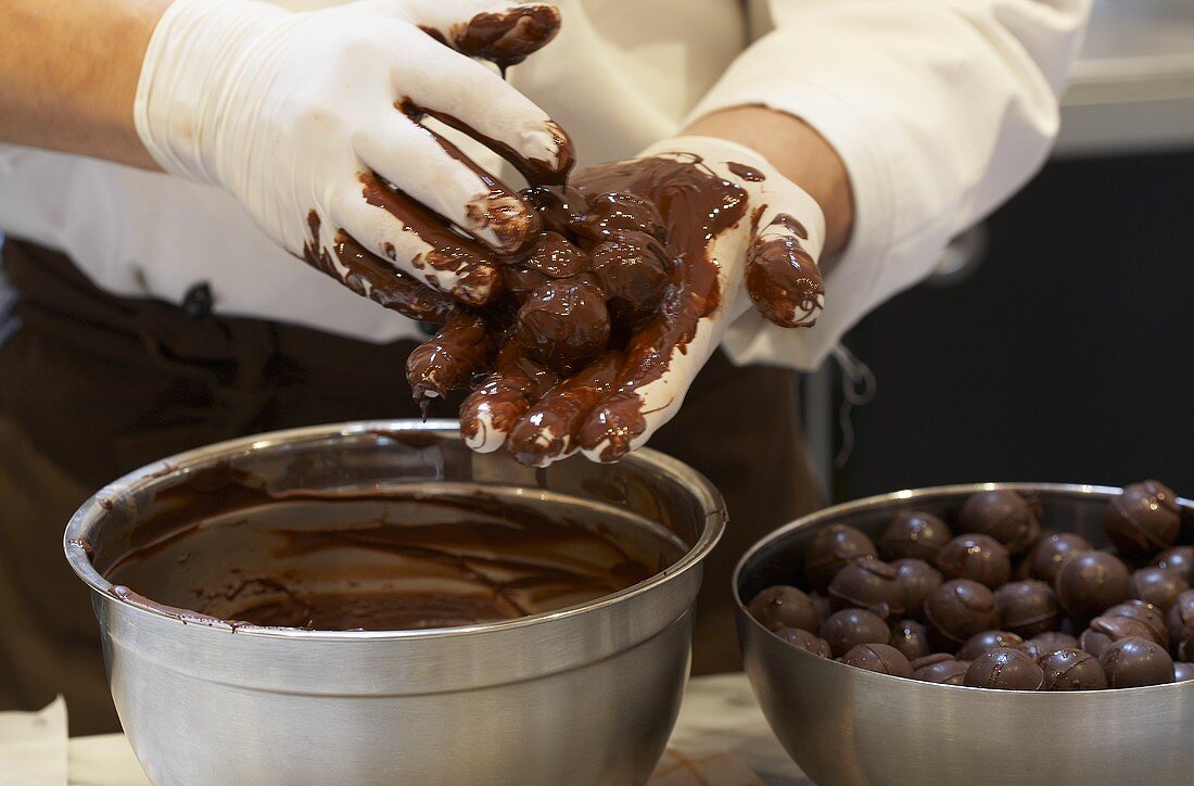 Pralinenkapsel werden in flüssiger Schokolade gerollt