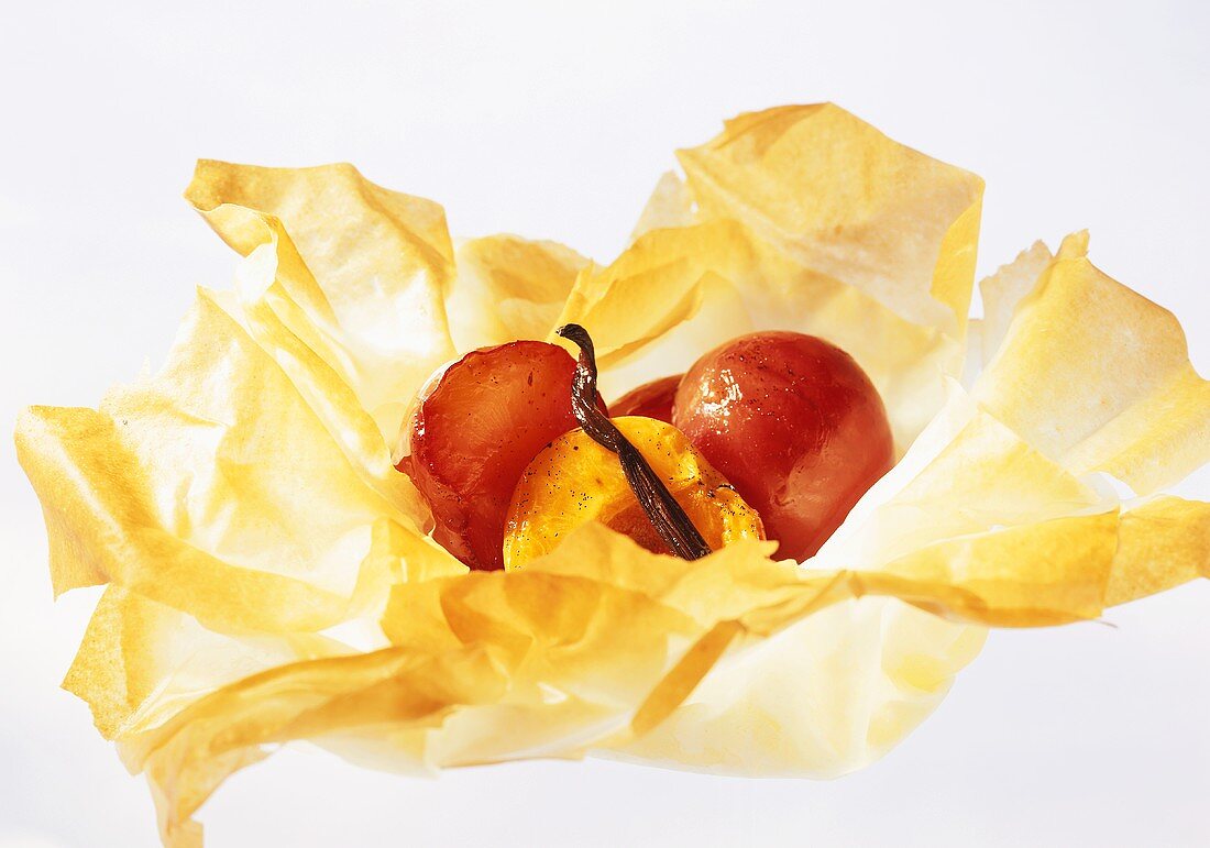 Plums baked in baking parchment with cinnamon stick