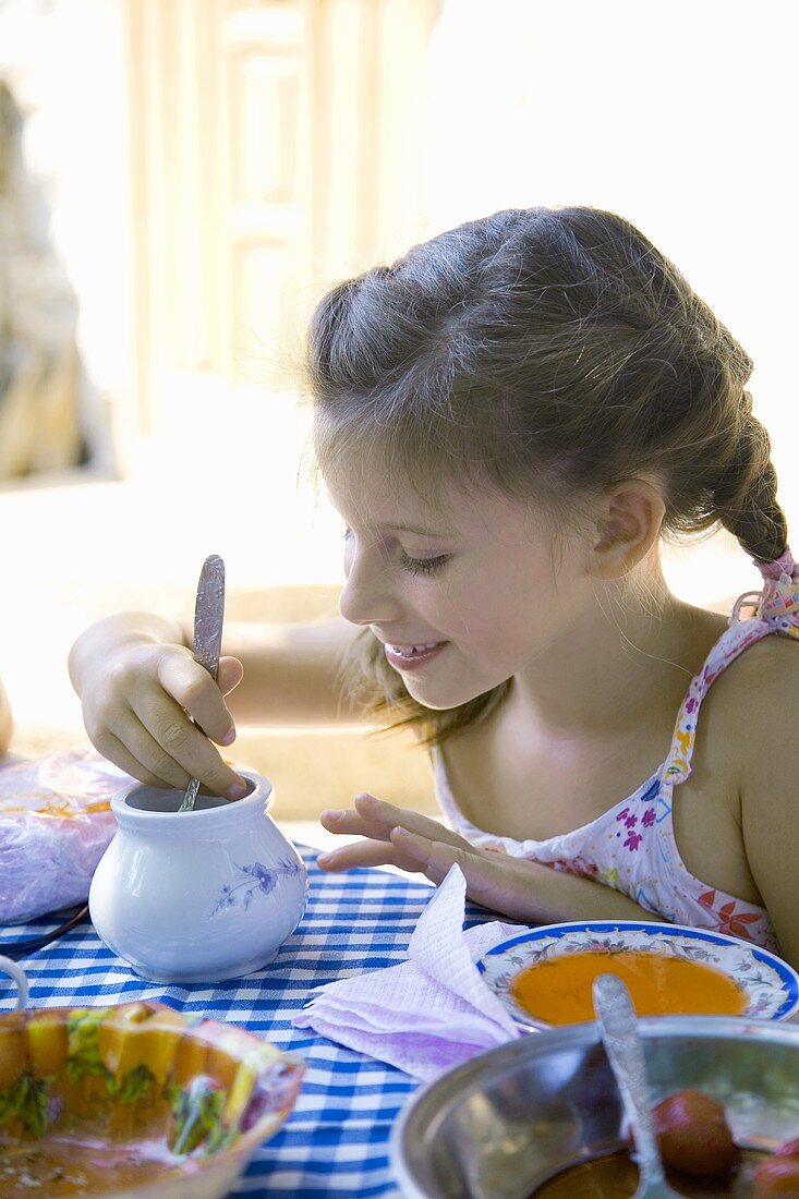 Mädchen isst Honig am Tisch (Bulgarien)