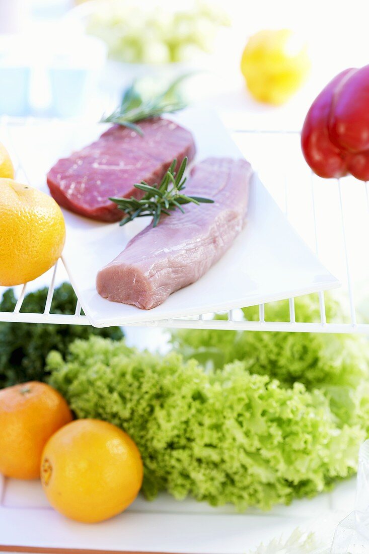 Schweinefilet, Rindersteak, Salat und Obst im Kühlschrank