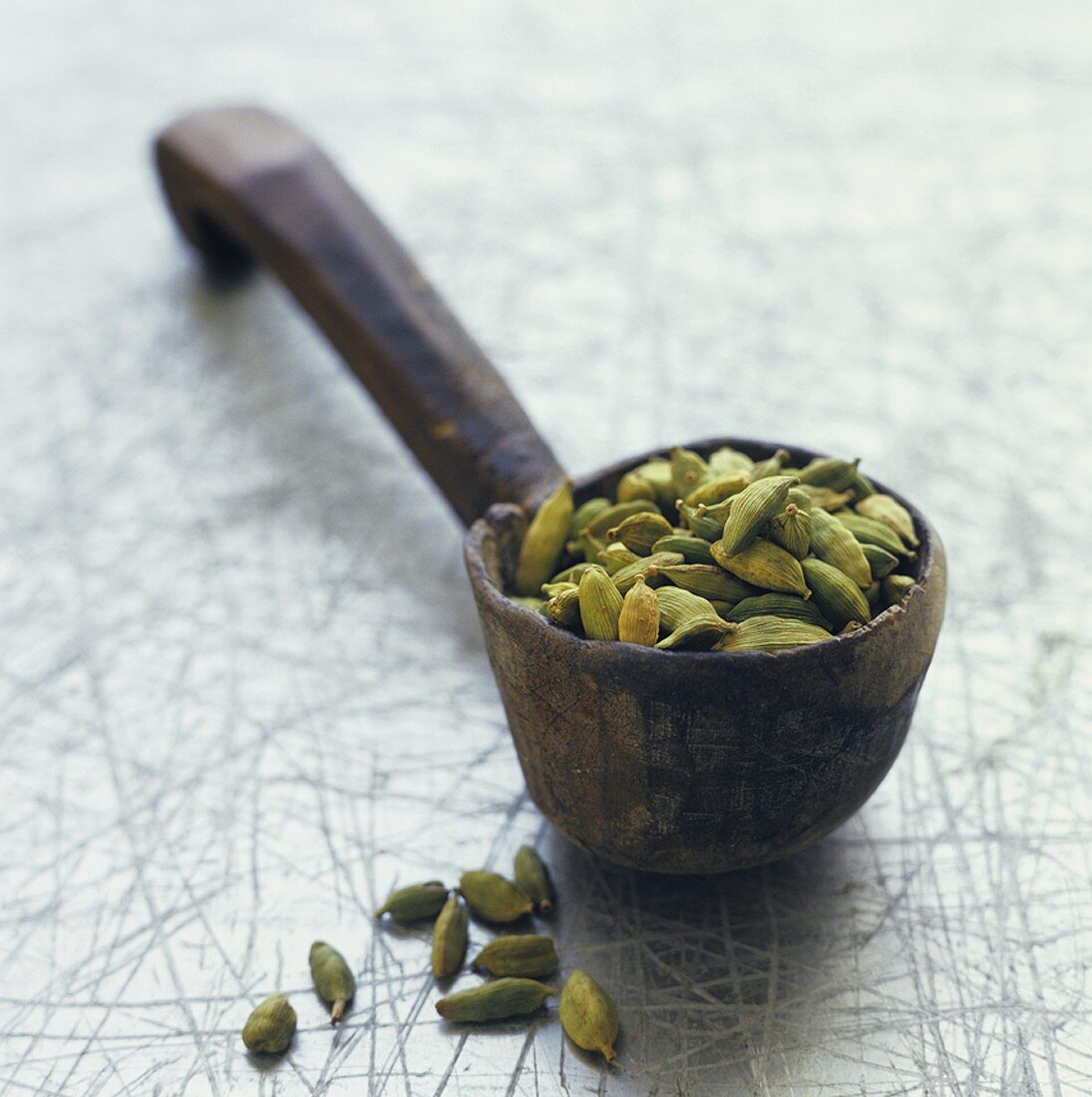 Cardamom pods in wooden spoon