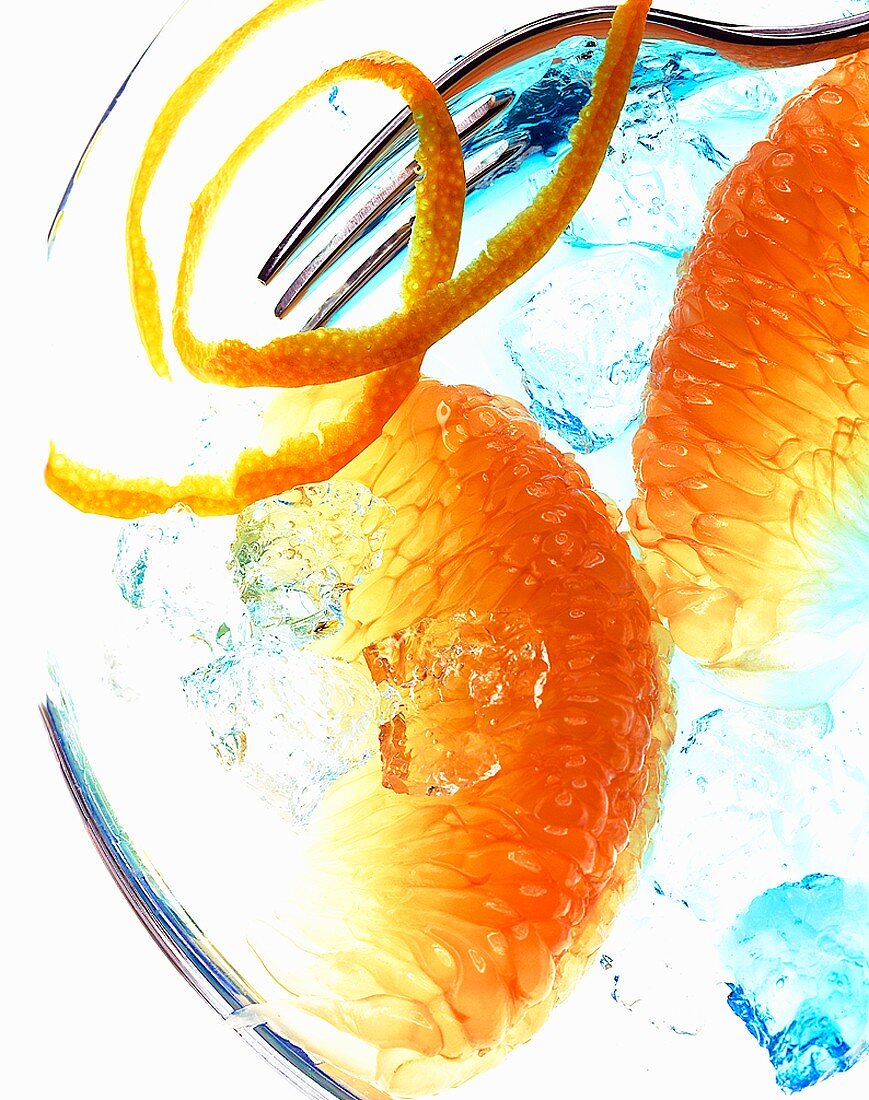 Orangenfilets, Orangenschale und Gabel auf Eis mit Curacao