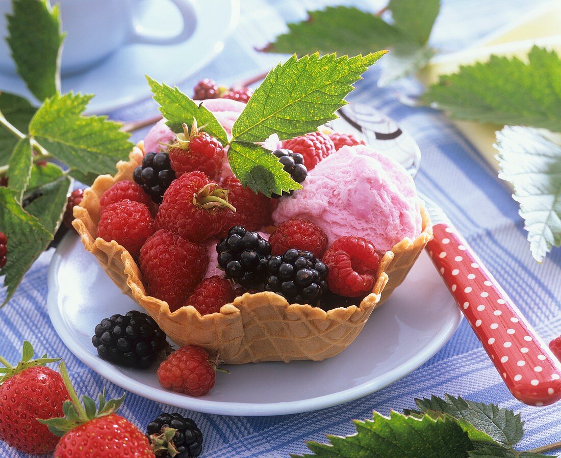 Raspberries and blackberries with ice cream in waffle bowl