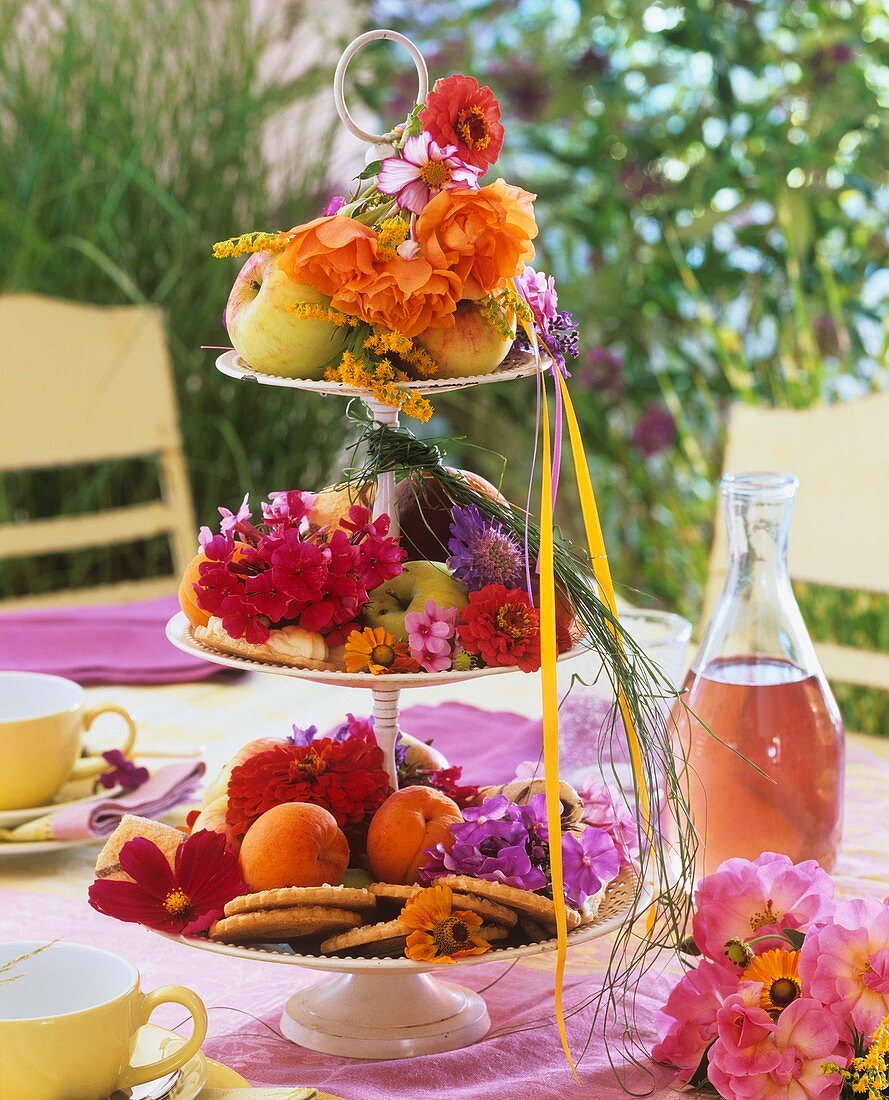 Etagere mit Blumen, Äpfeln, Aprikosen und Keksen