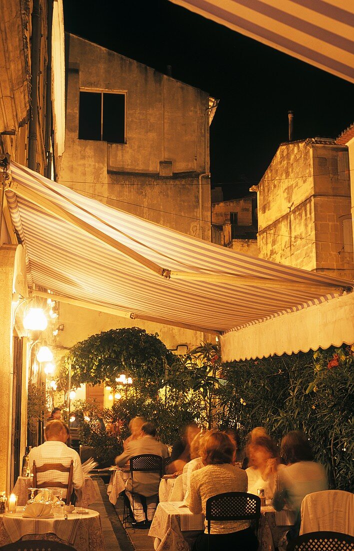 Terrasse eines französischen Restaurants mit historischer Stadtkulisse im Abendlicht