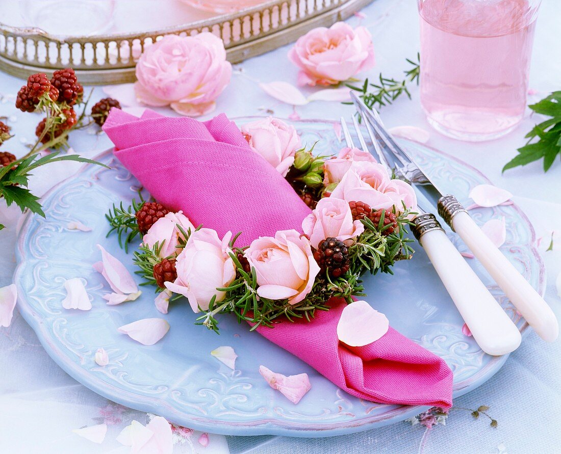 Festive place-setting with napkin ring of roses & rosemary