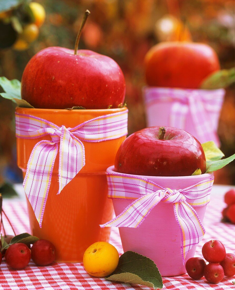 Äpfel auf bunten Bechern als Tischdeko