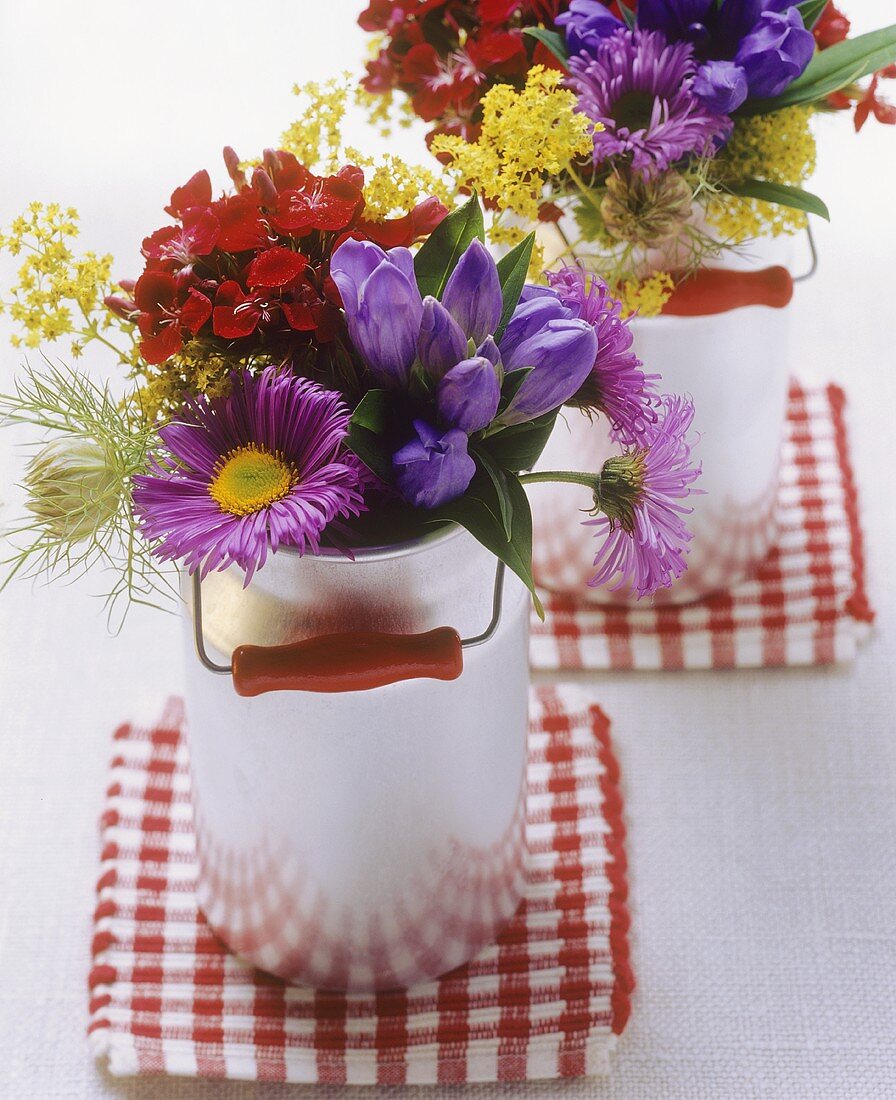 Posies of colourful meadow flowers in small milk cans