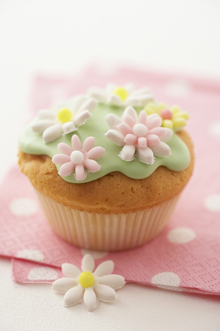 Muffin mit grünem Zuckerguss und Zuckerblüten