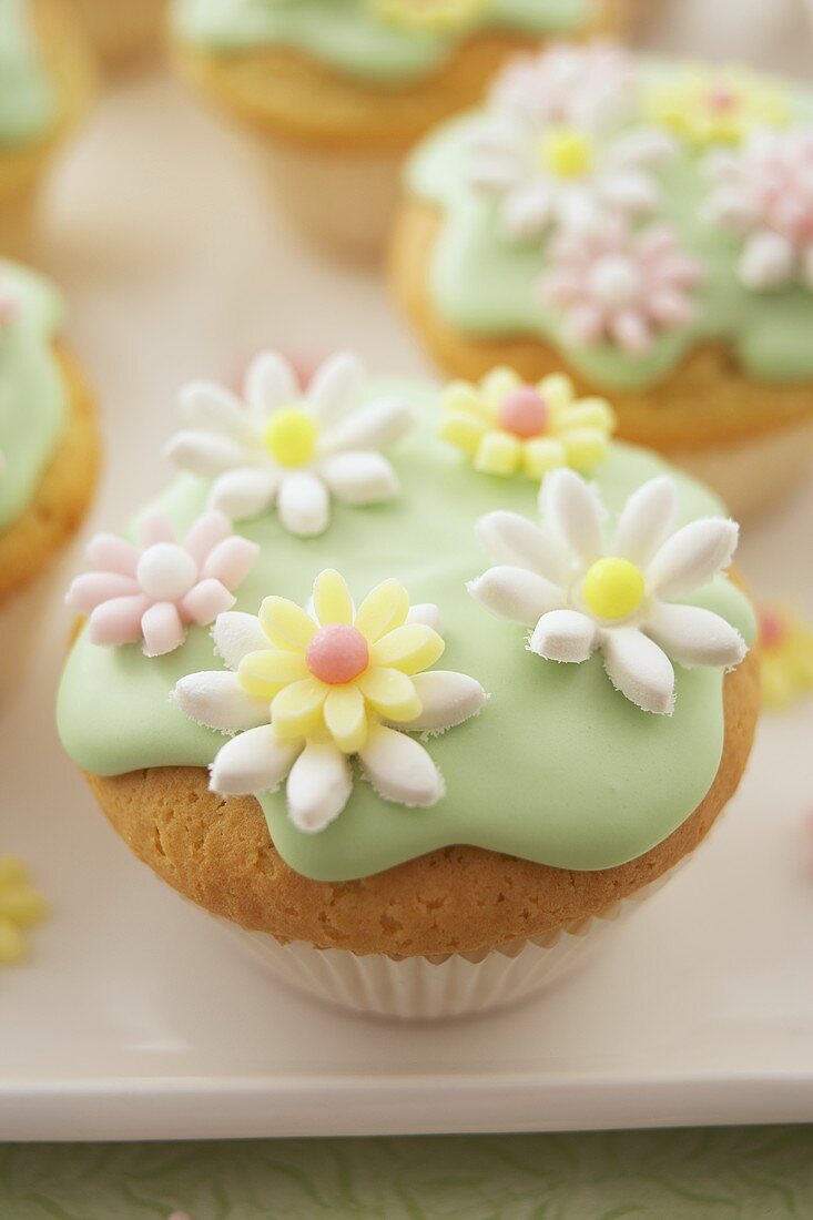 Muffins with green icing and sugar flowers (close-up)