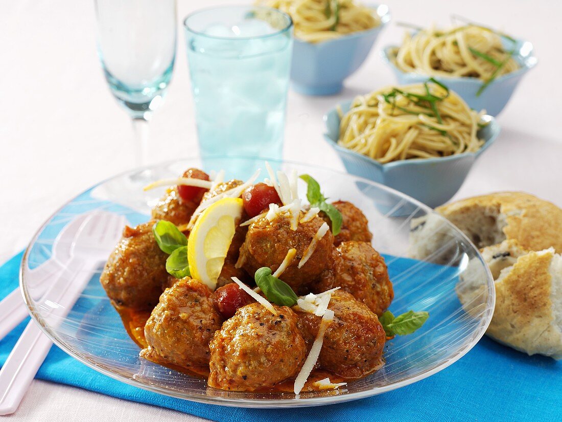 Hackbällchen mit Tomatensauce, im Hintergrund Spaghetti