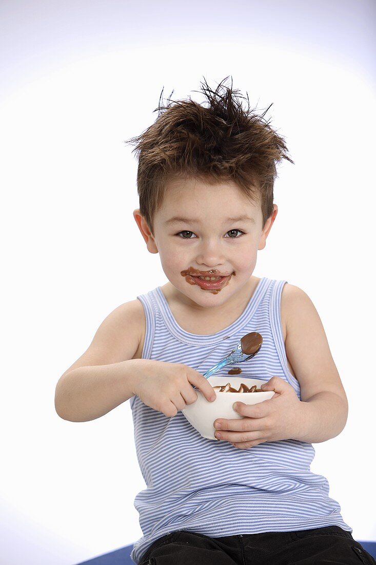 Small boy holding bowl of chocolate pudding