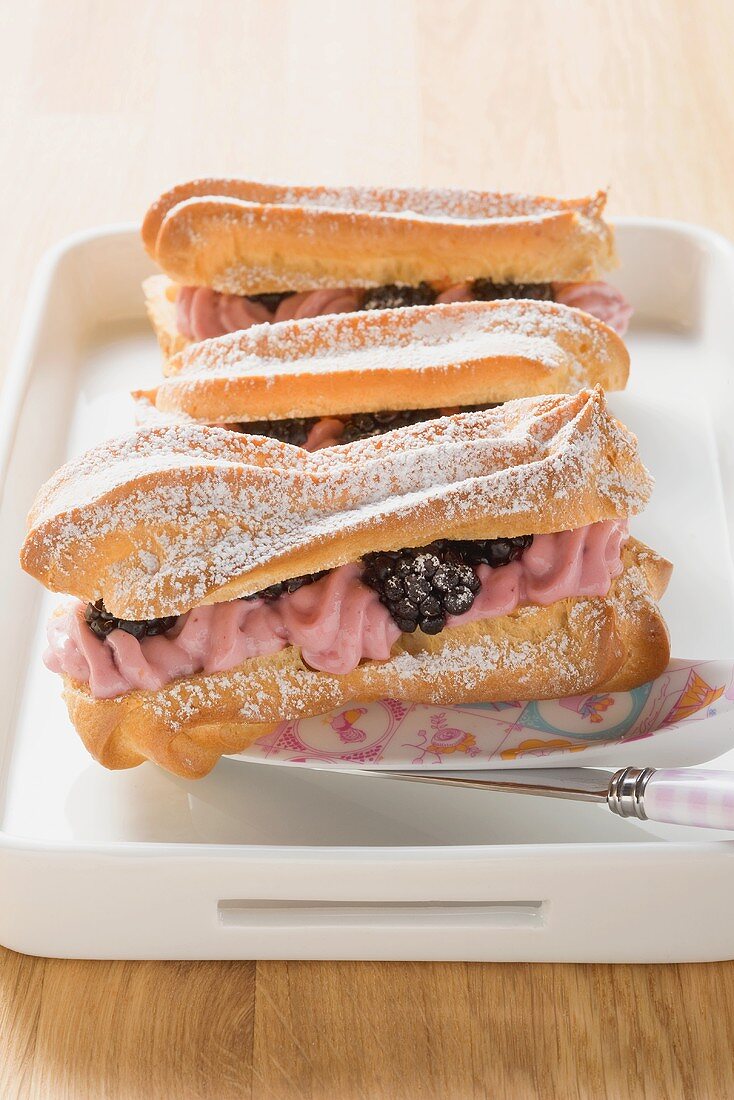 Eclairs filled with lemon cream and blackberries