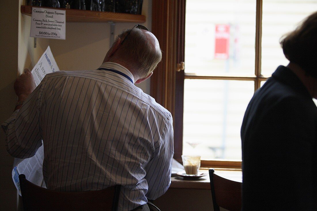 Mann liest Zeitung im Café