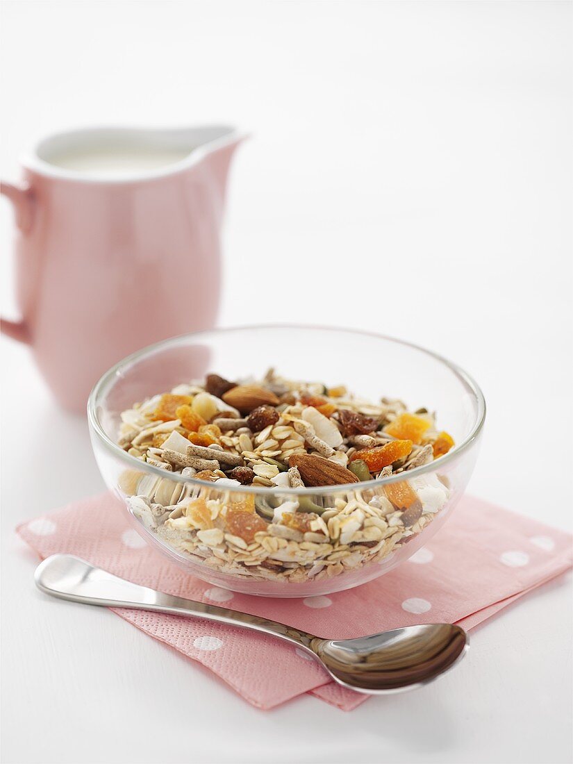Muesli with nuts and dried fruit, small jug of milk