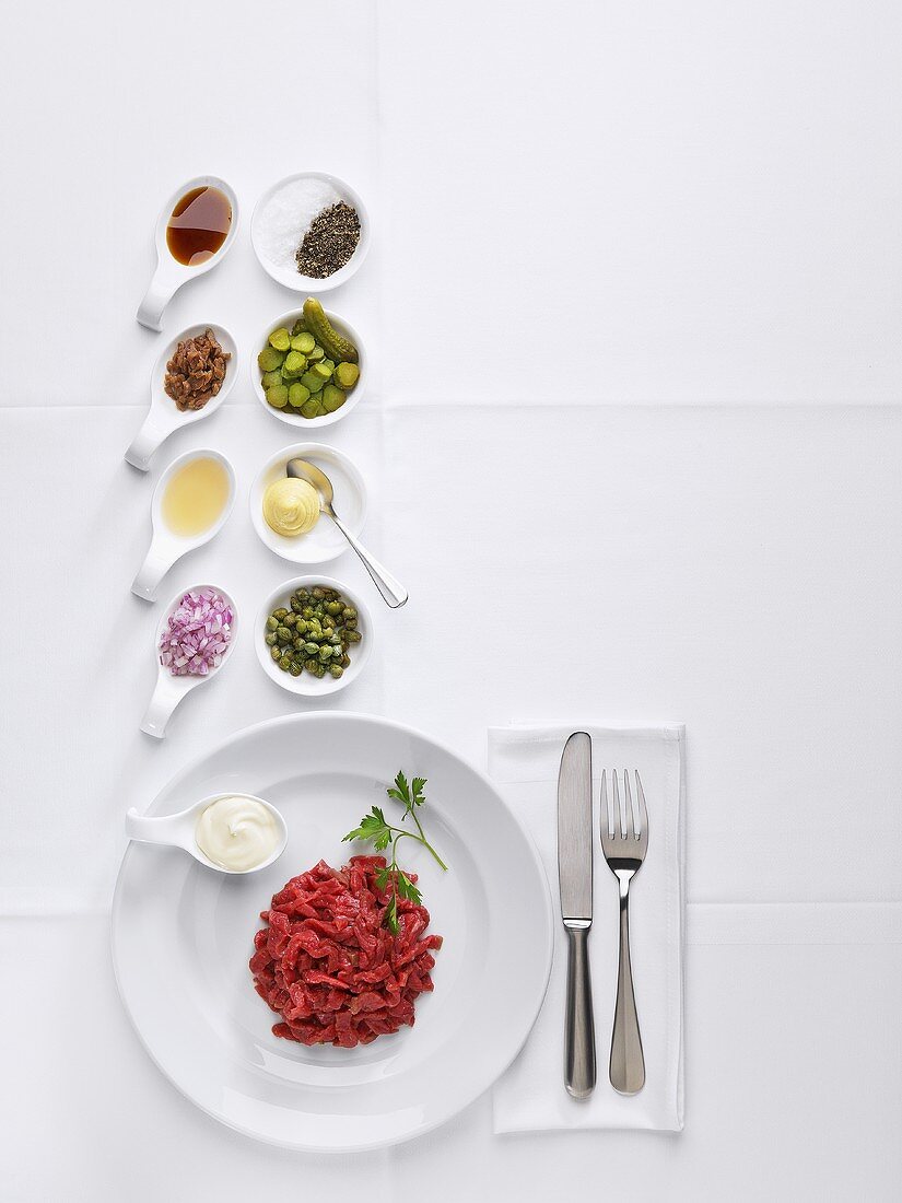 Ingredients for steak tartare on white tablecloth