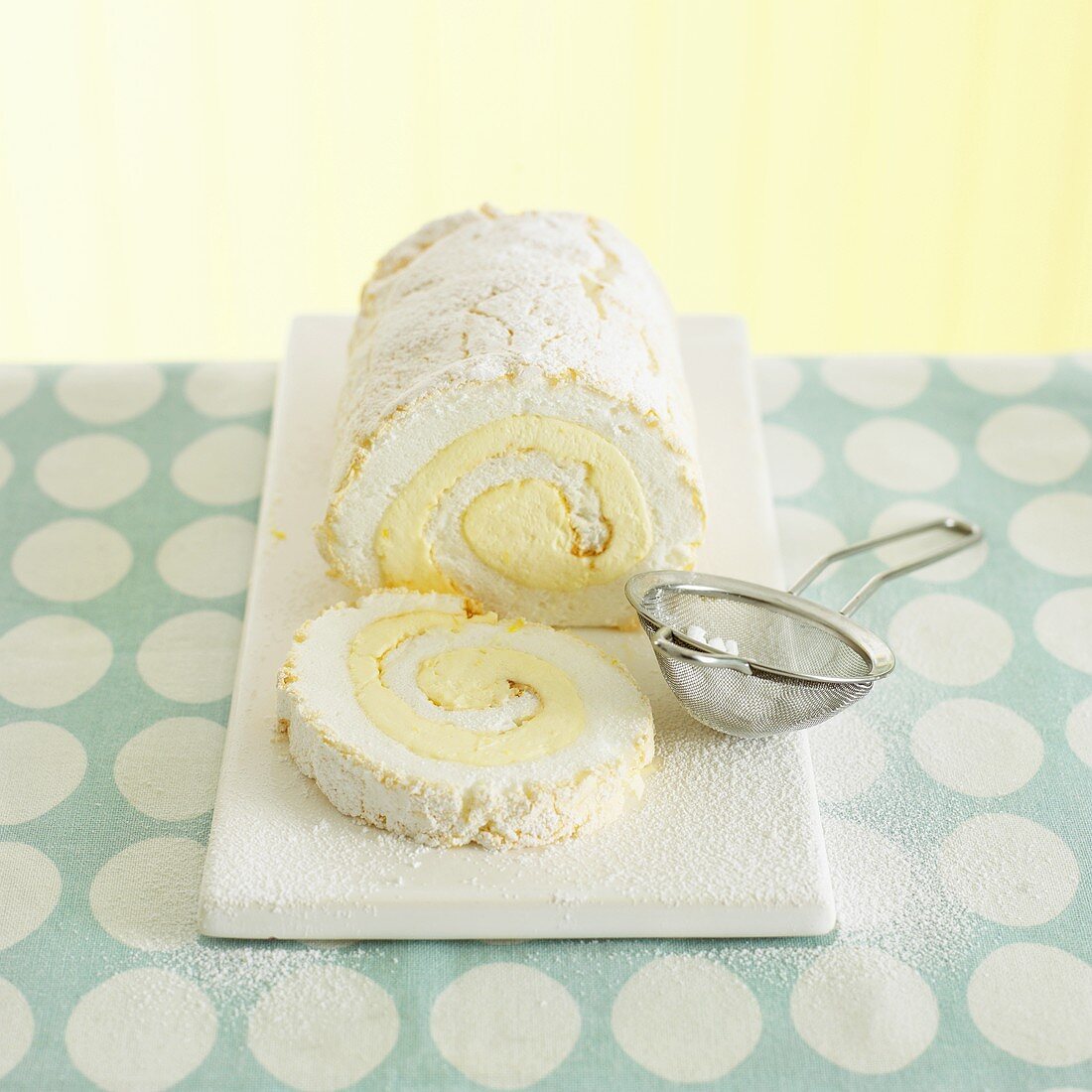 Lemon meringue roulade with icing sugar, a slice cut