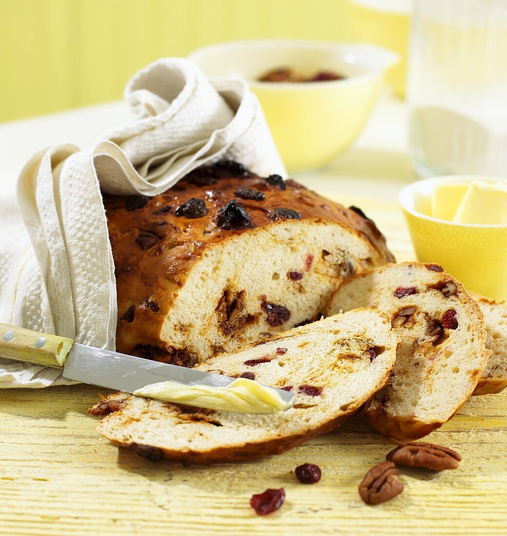 White bread with cranberries and caramelised pecans, partly sliced