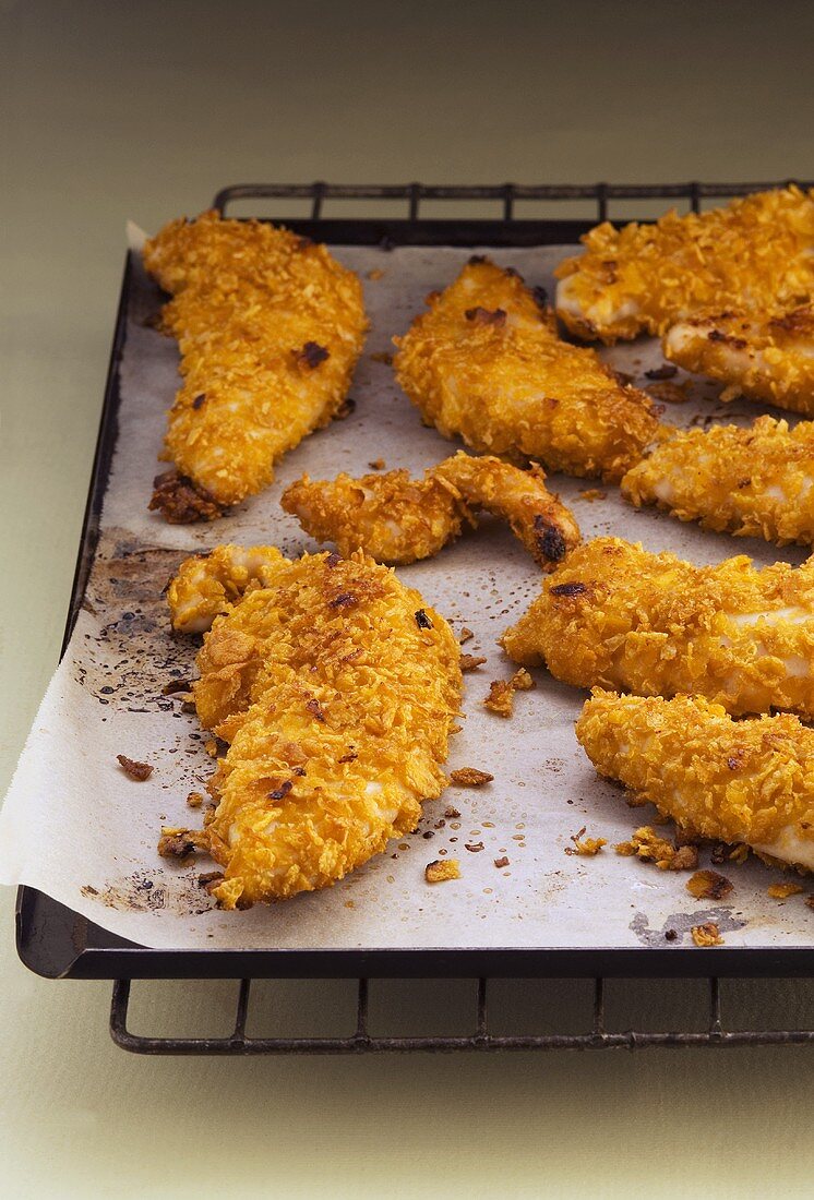 Strips of chicken with crispy coating on baking tray