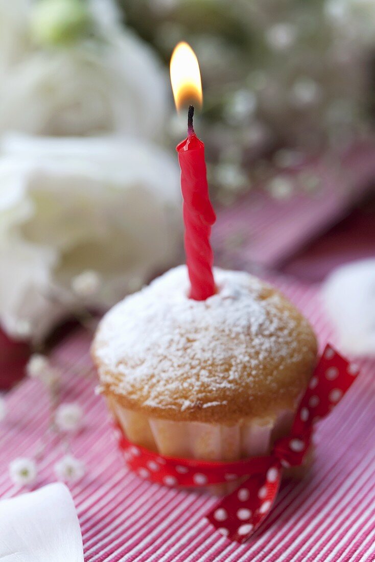 Muffin with icing sugar and candle
