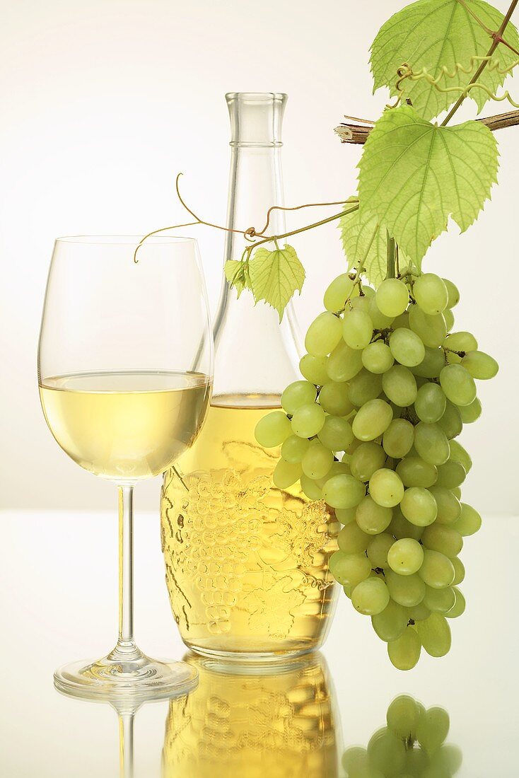 Weißwein in Glas und Flasche, grüne Trauben