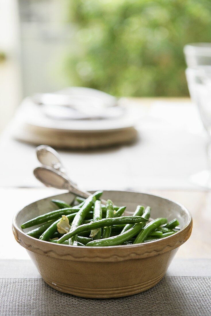 Grüne Bohnen mit Mandeln in Keramikschüssel auf Tisch