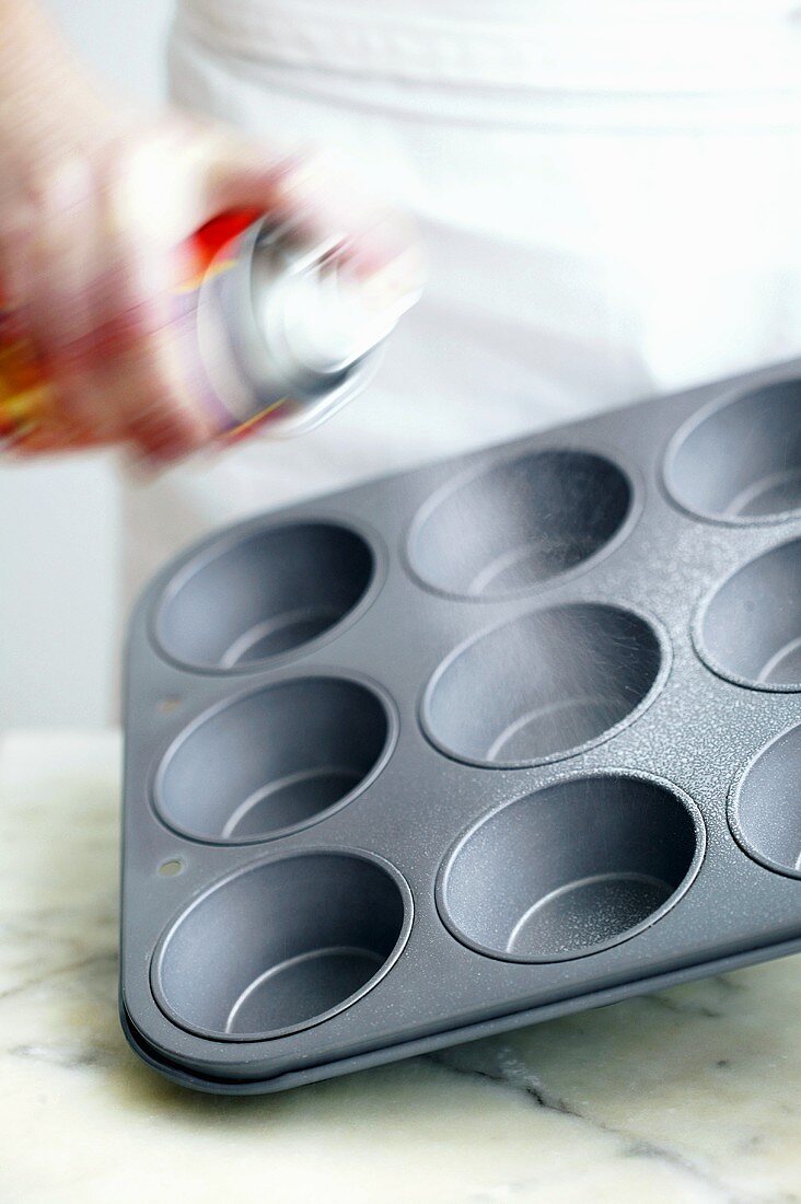 Spraying muffin tin with oil